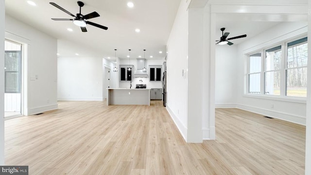 unfurnished living room featuring ceiling fan and light hardwood / wood-style floors