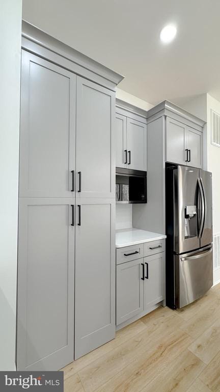 kitchen with gray cabinetry, stainless steel fridge, and light hardwood / wood-style flooring