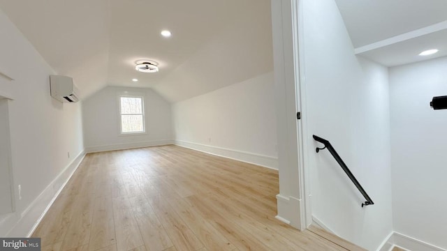 bonus room featuring lofted ceiling, a wall mounted AC, and light hardwood / wood-style flooring