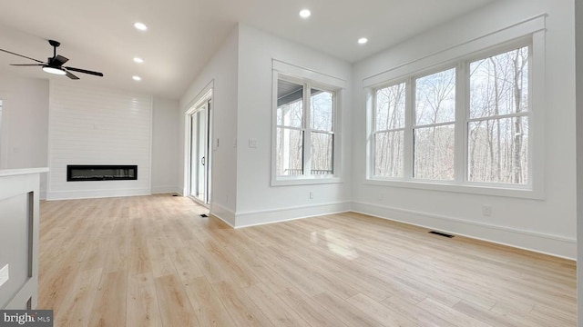 unfurnished living room with light wood-style floors, a fireplace, and a wealth of natural light