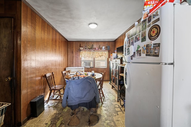 dining space featuring cooling unit, light floors, and wood walls