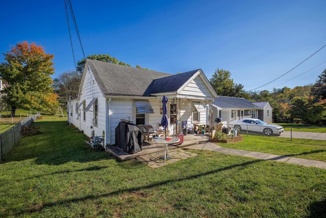 exterior space featuring a patio area, a shingled roof, a front yard, and fence