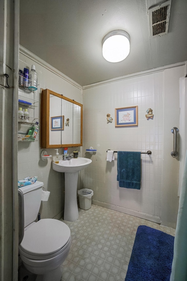 half bath featuring visible vents, toilet, ornamental molding, tile patterned floors, and a sink