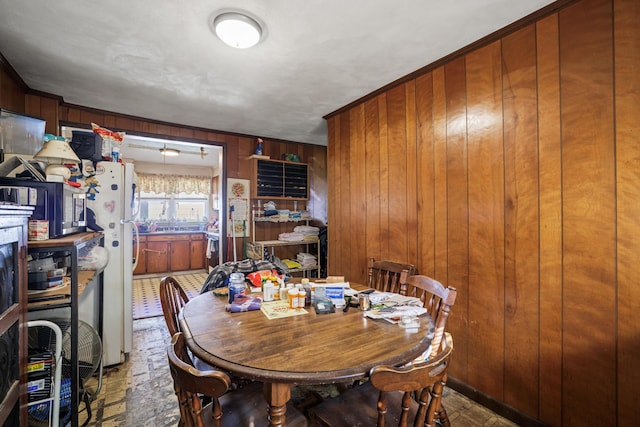 dining room with tile patterned floors and wood walls