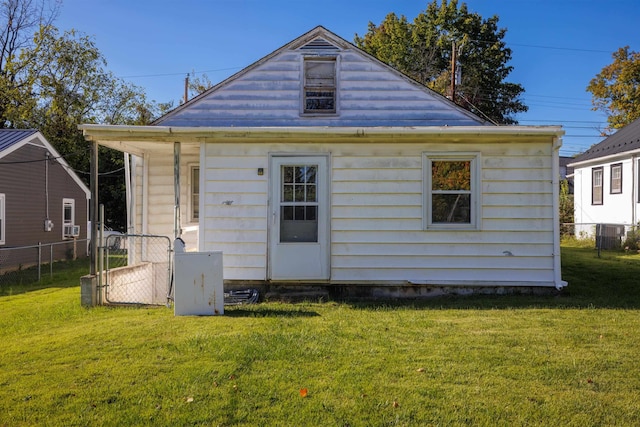 back of house with a gate, a lawn, and fence