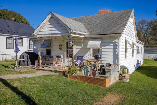 back of house with a patio, a yard, and roof with shingles