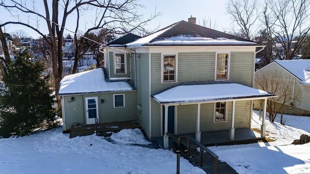 snow covered rear of property with covered porch