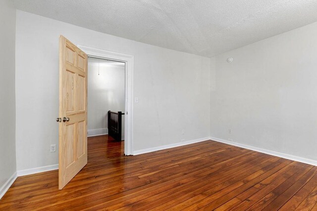 spare room with a textured ceiling and dark hardwood / wood-style flooring