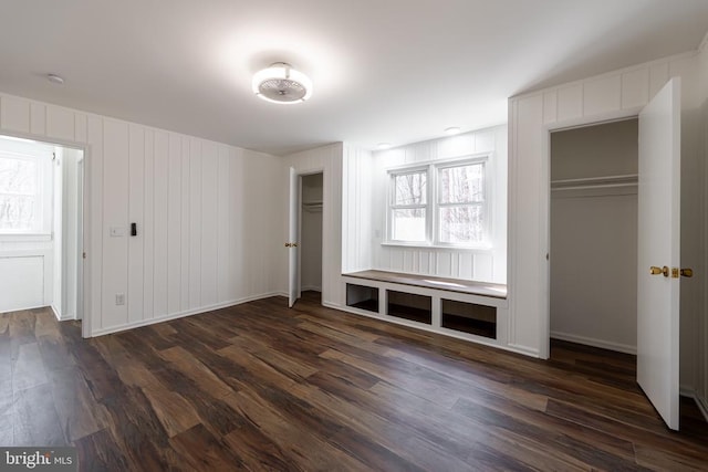 unfurnished bedroom featuring dark wood-style flooring and two closets