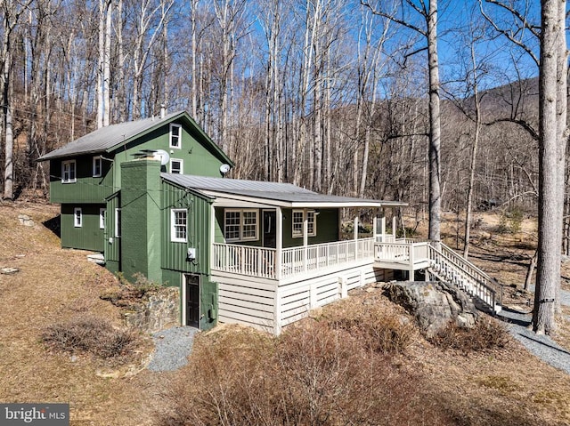 rustic home with a porch, metal roof, a wooded view, and stairs