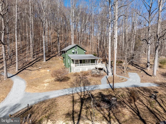 view of front facade featuring driveway, a forest view, and a porch