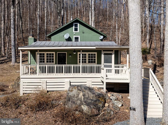 chalet / cabin with covered porch, metal roof, a standing seam roof, and a view of trees