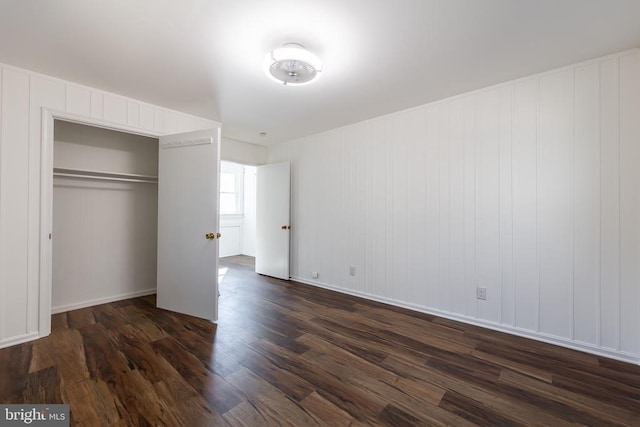 unfurnished bedroom featuring a closet and dark wood-style flooring