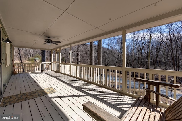 wooden deck featuring a forest view and a ceiling fan