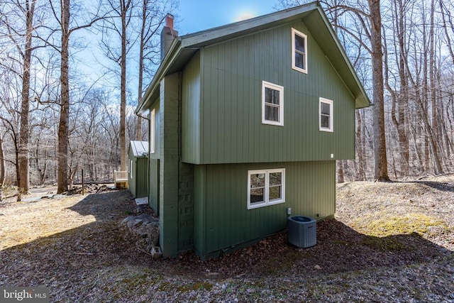 view of property exterior with central AC and a chimney