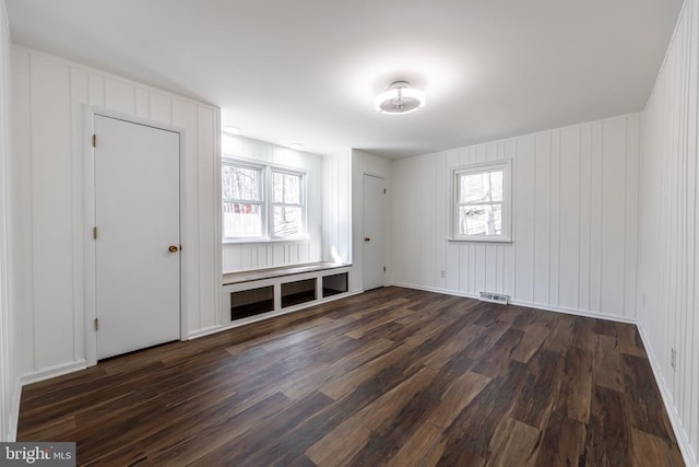 empty room with a wealth of natural light, visible vents, and dark wood-style flooring