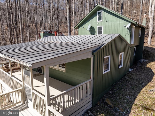 view of home's exterior featuring metal roof, a standing seam roof, and a view of trees