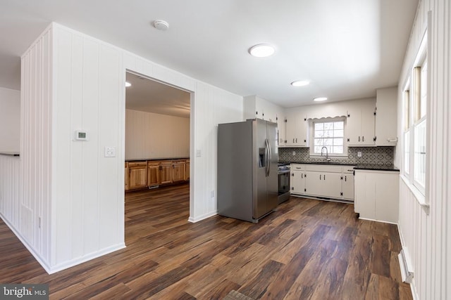 kitchen with dark countertops, appliances with stainless steel finishes, dark wood-type flooring, white cabinetry, and a sink