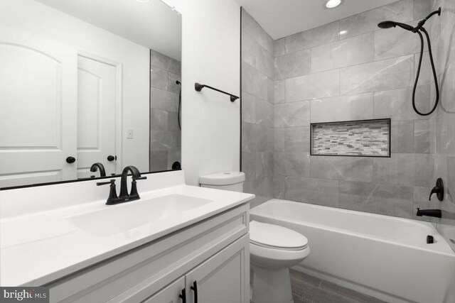 full bathroom with vanity, wood-type flooring, toilet, and tiled shower / bath