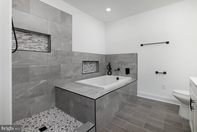 bathroom featuring vanity, tiled tub, and toilet