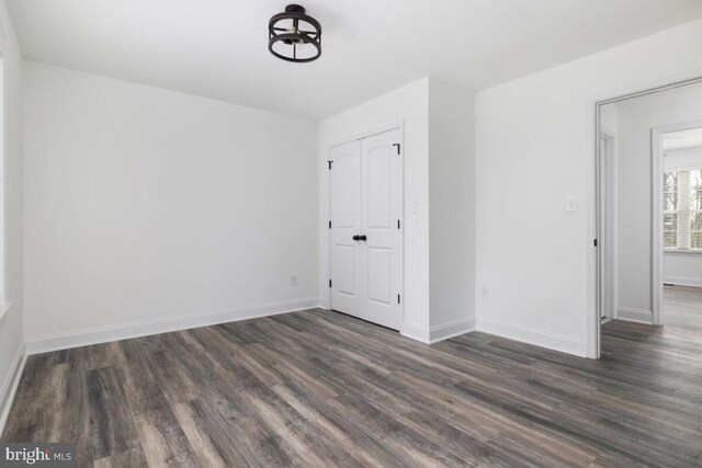 empty room featuring baseboards and dark wood-style flooring