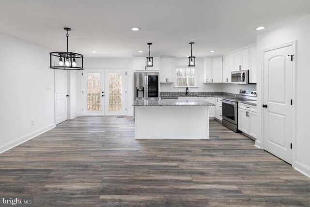 kitchen with a kitchen island, white cabinetry, appliances with stainless steel finishes, and decorative light fixtures