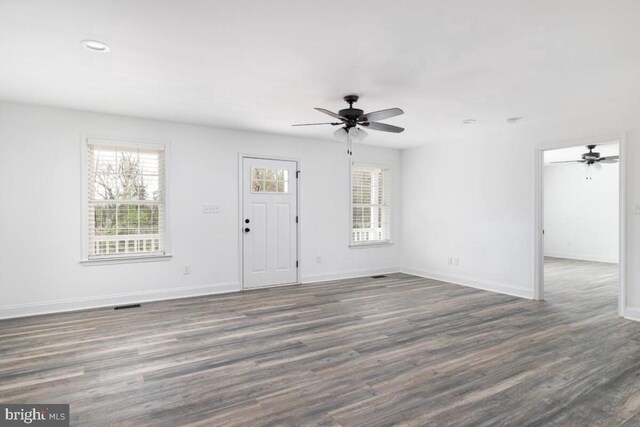 unfurnished living room featuring dark wood-type flooring and ceiling fan