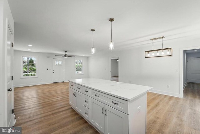 unfurnished living room featuring a ceiling fan, visible vents, baseboards, and dark wood-type flooring