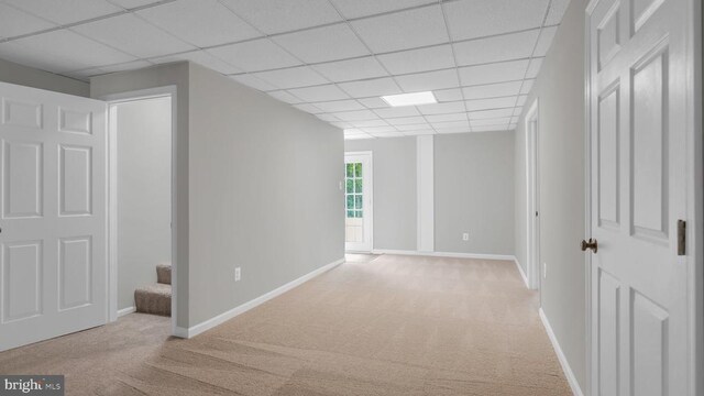 interior space featuring a paneled ceiling and light colored carpet