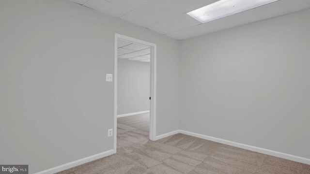 carpeted spare room featuring a paneled ceiling