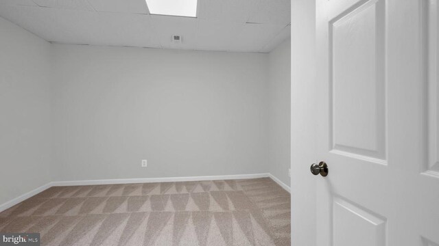 unfurnished room with a drop ceiling and light colored carpet