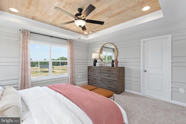 bedroom featuring multiple windows, a tray ceiling, wooden ceiling, and light colored carpet