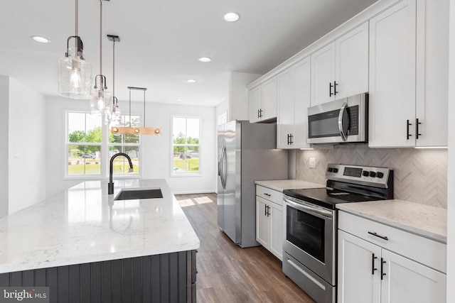 kitchen featuring stainless steel appliances, sink, pendant lighting, and white cabinets