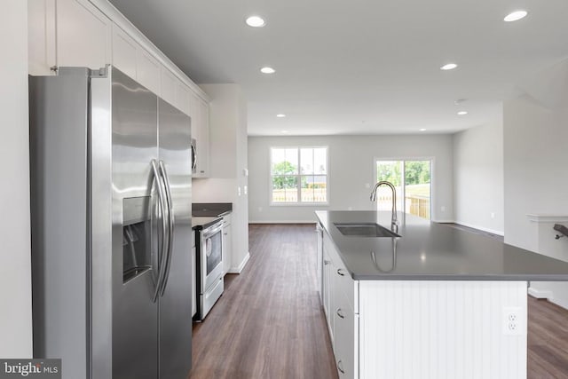 kitchen featuring appliances with stainless steel finishes, white cabinetry, sink, dark wood-type flooring, and a center island with sink