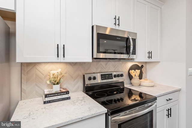 kitchen with light stone counters, stainless steel appliances, decorative backsplash, and white cabinets