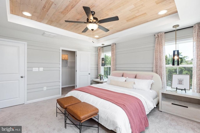 carpeted bedroom featuring ceiling fan, a tray ceiling, a closet, and wooden ceiling