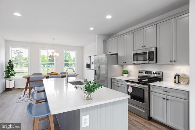 kitchen featuring appliances with stainless steel finishes, sink, gray cabinetry, and pendant lighting