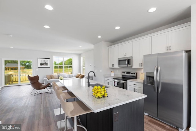 kitchen with white cabinets, appliances with stainless steel finishes, sink, and a kitchen island with sink