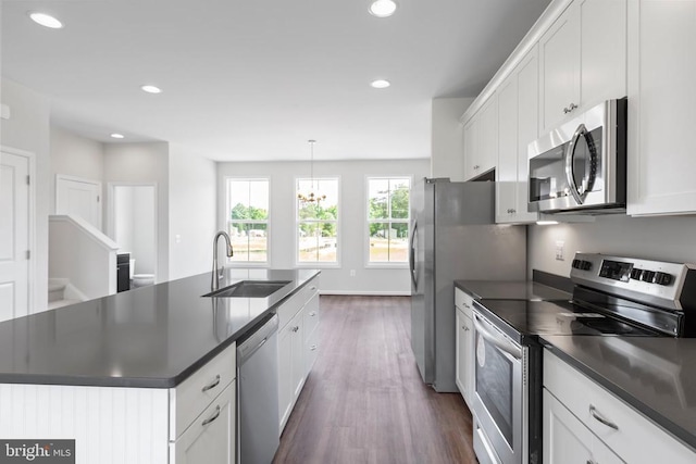 kitchen featuring appliances with stainless steel finishes, pendant lighting, an island with sink, sink, and white cabinets