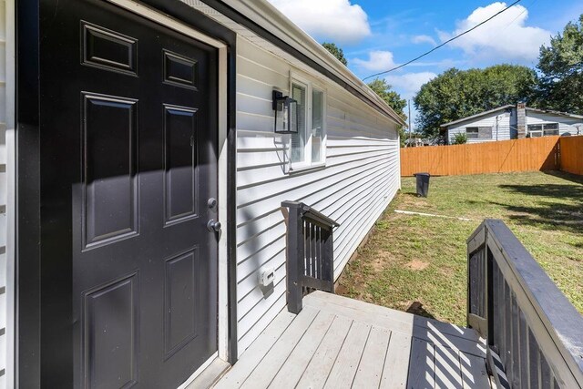 view of exterior entry with a wooden deck and a yard