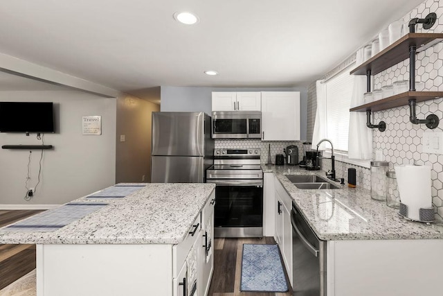 kitchen with sink, appliances with stainless steel finishes, white cabinetry, light stone counters, and dark hardwood / wood-style flooring