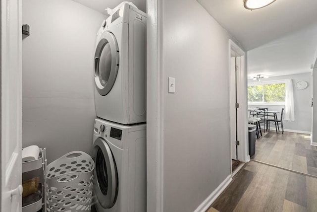 laundry area featuring wood-type flooring and stacked washer and clothes dryer