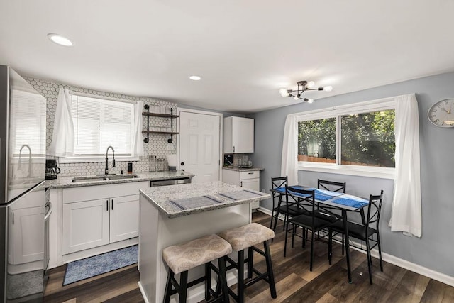 kitchen with white cabinetry, stainless steel appliances, sink, and a kitchen island