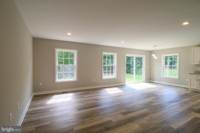unfurnished living room featuring baseboards, recessed lighting, dark wood-style flooring, and a wealth of natural light