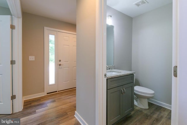 bathroom with visible vents, wood finished floors, vanity, baseboards, and toilet