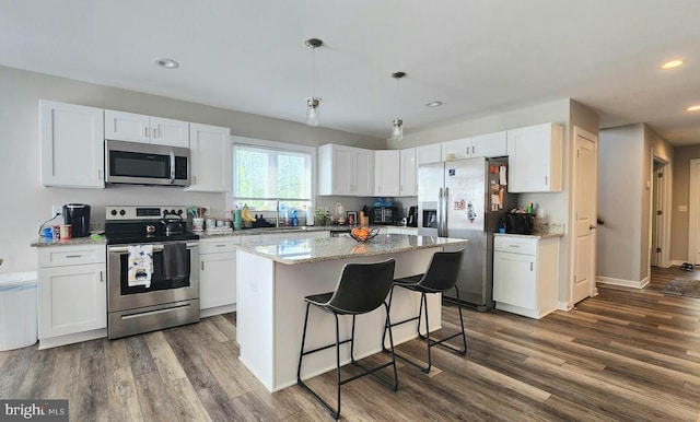 kitchen with light stone countertops, dark wood finished floors, stainless steel appliances, recessed lighting, and white cabinetry