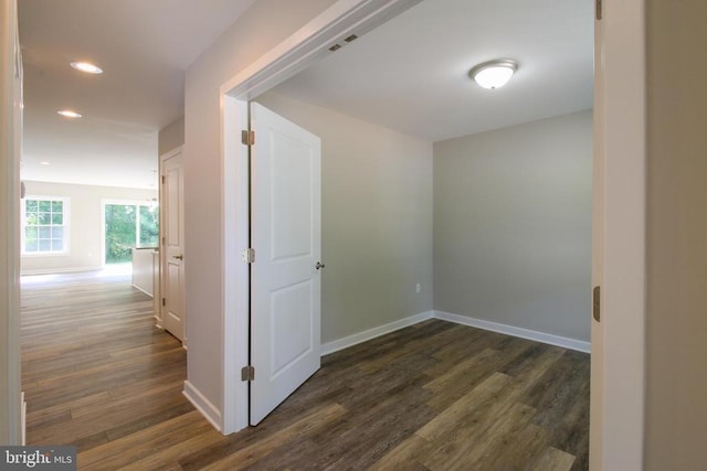 corridor with baseboards, recessed lighting, and dark wood-type flooring