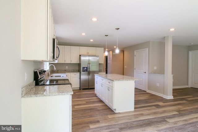 kitchen featuring a kitchen island, wood finished floors, a sink, stainless steel appliances, and recessed lighting