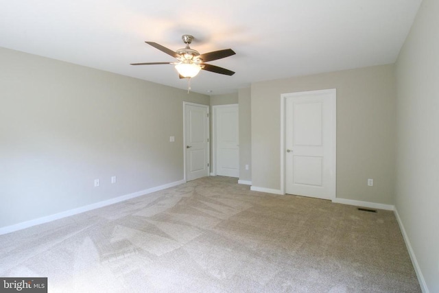 unfurnished bedroom with baseboards, visible vents, a ceiling fan, and light colored carpet