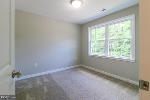 carpeted empty room featuring baseboards and visible vents